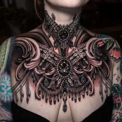 Ornate jewelry tattoo on chest and neck, intricate black designs with gem-like details.