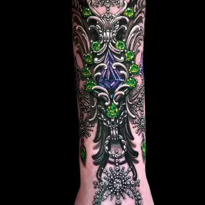 Intricate forearm tattoo with green and purple jewels
