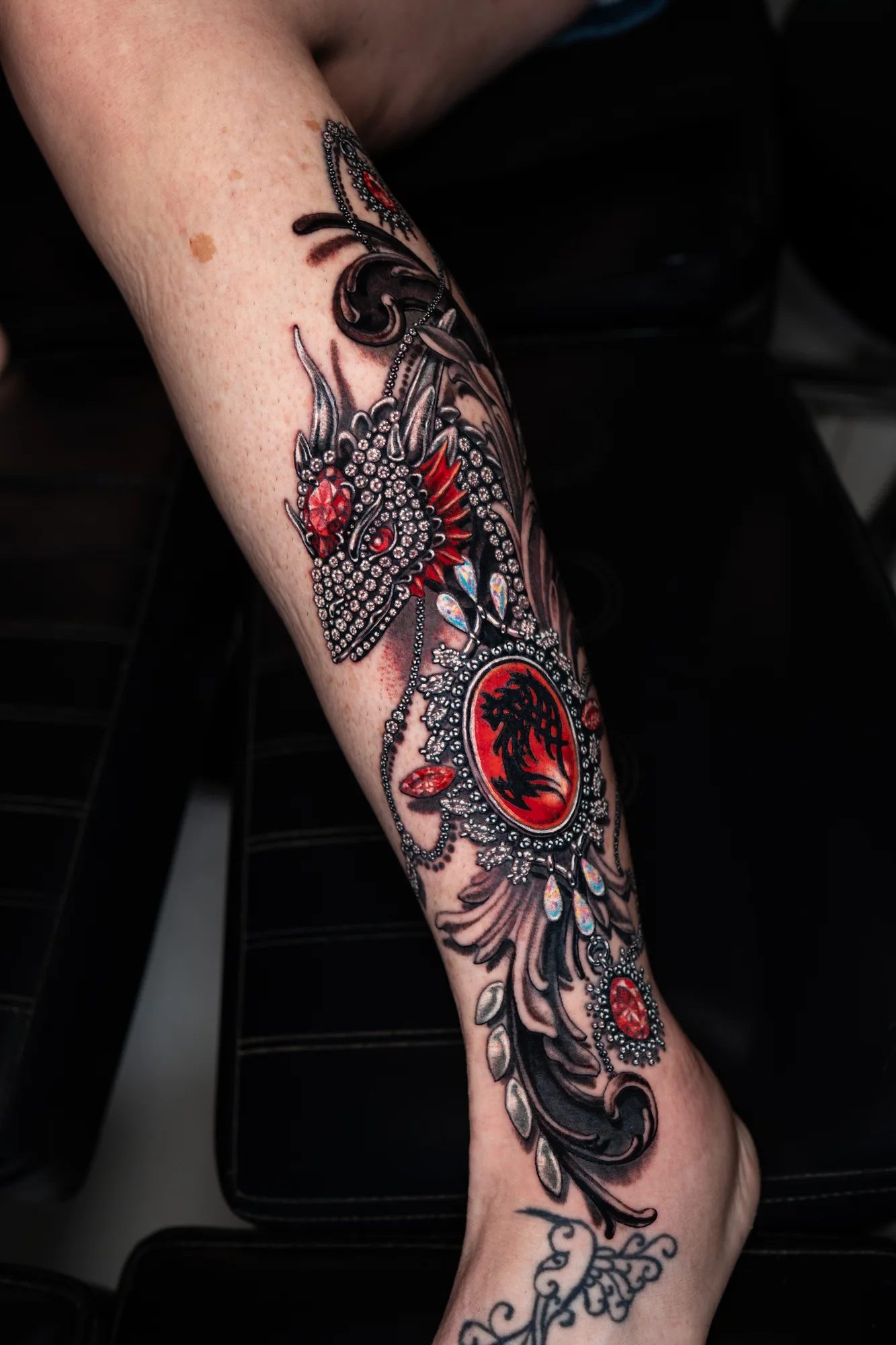 Intricate dragon tattoo on the lower leg with red accents