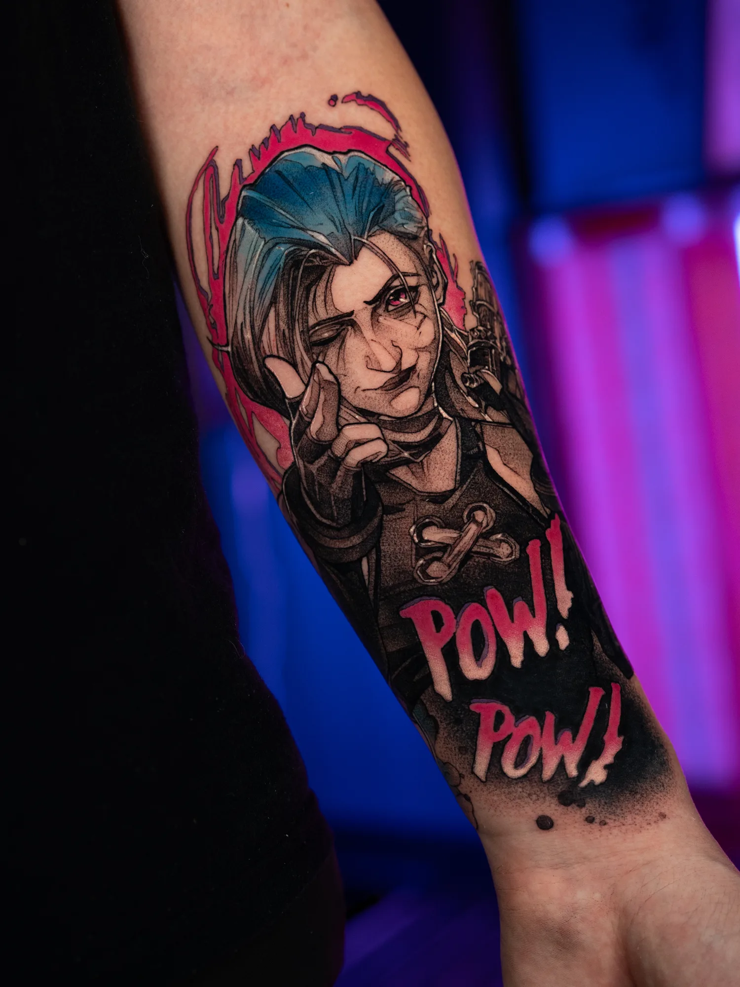 Tattoo of a character with blue hair pointing, word 'POW!' in pink.