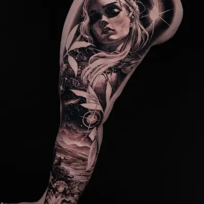 Female portrait tattoo with celestial and landscape elements on arm.