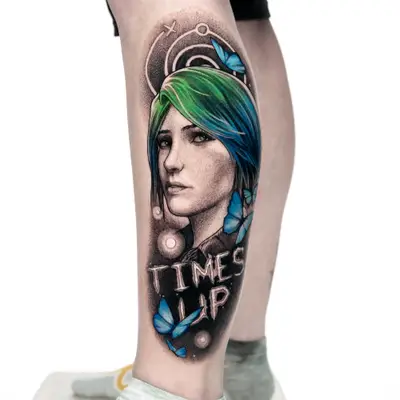 Colorful portrait tattoo of a woman with blue hair and butterflies, text reads 'TIME'S UP'.