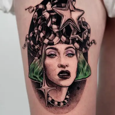 A bold tattoo of a woman with snakes and stars on her head, featuring green hair and striking makeup.