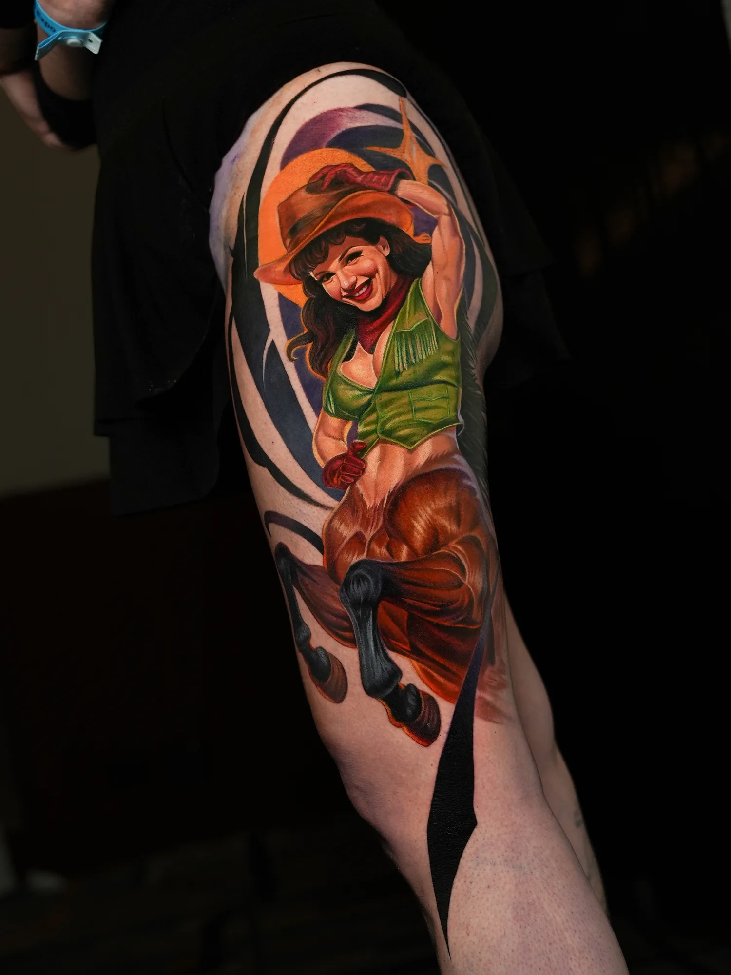 A vibrant, detailed realistic pin-up of a woman in a cowboy hat tattooed on a thigh.