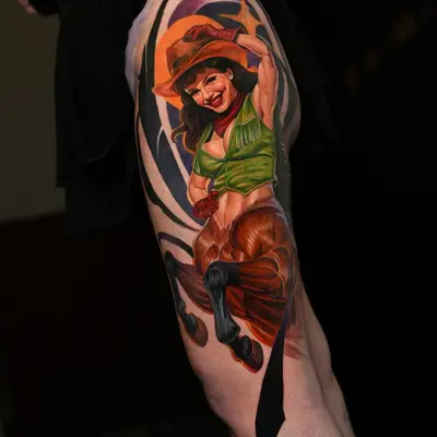 A vibrant, detailed realistic pin-up of a woman in a cowboy hat tattooed on a thigh.