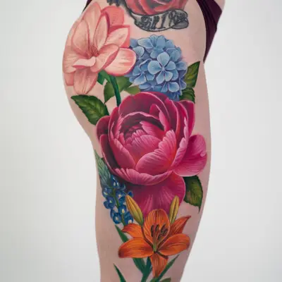 Vibrant floral tattoo on thigh featuring various colorful flowers.