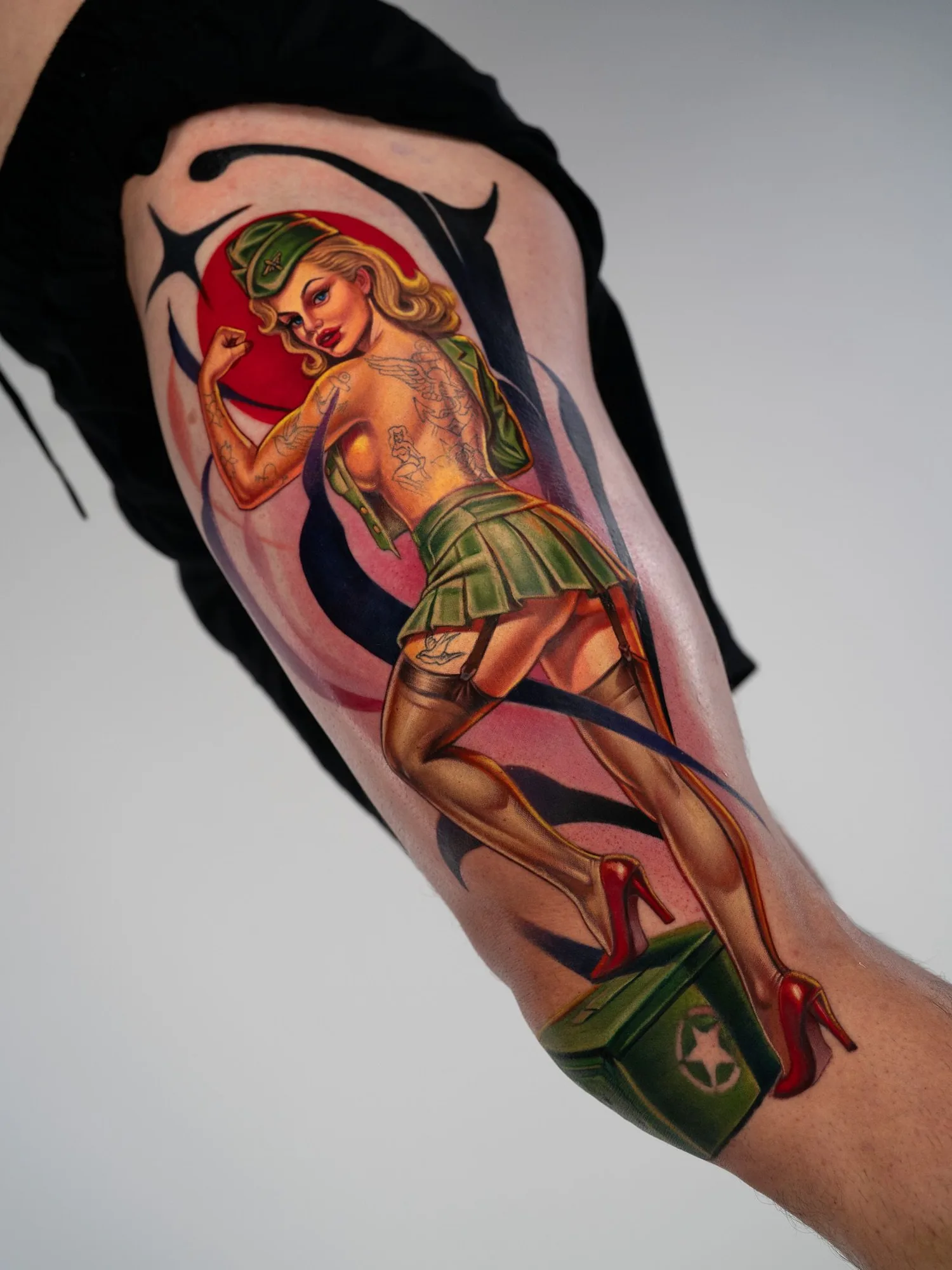 Colorful pin-up tattoo of a woman in military attire on the arm.
