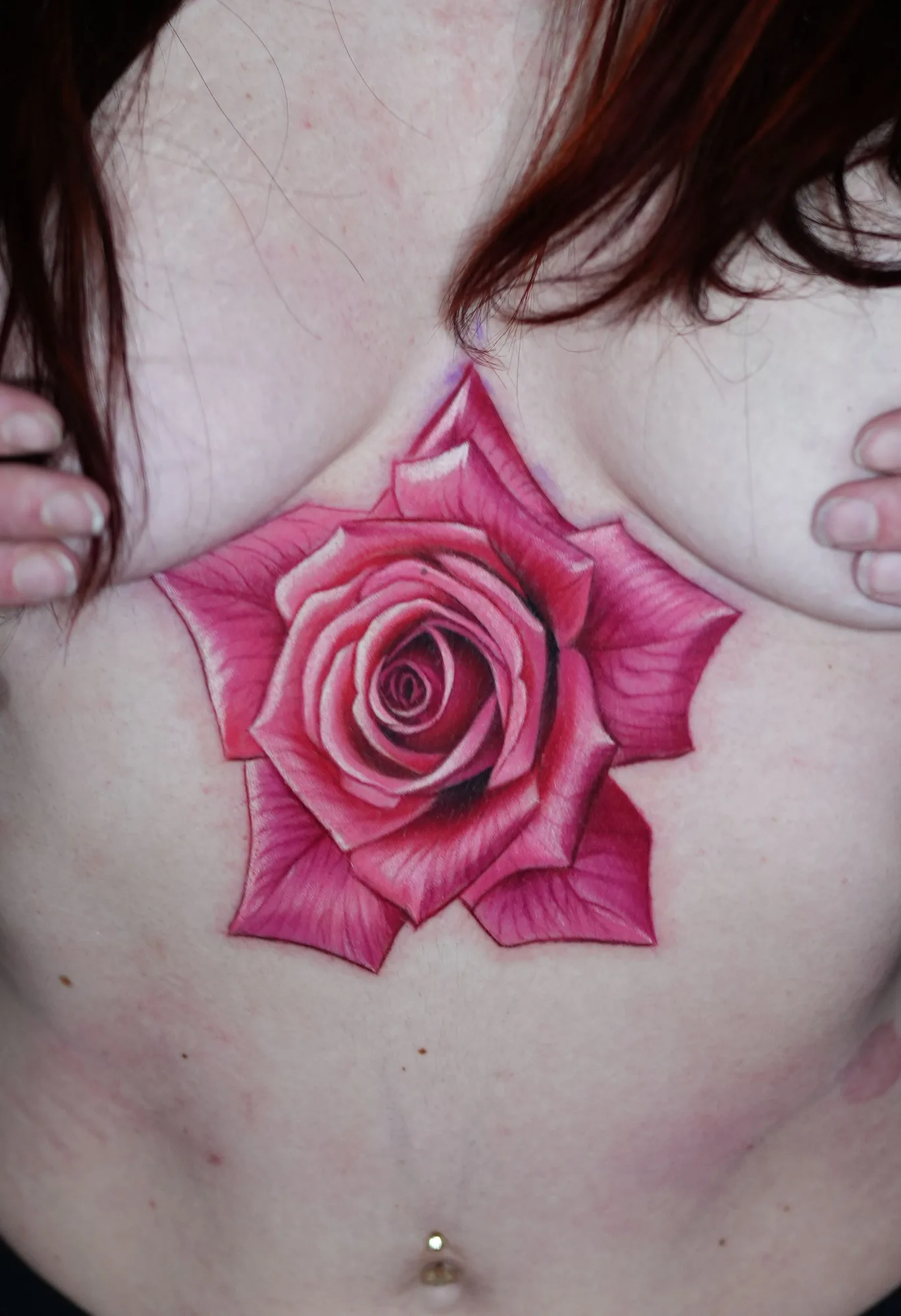 Realistic pink rose tattoo on chest area.