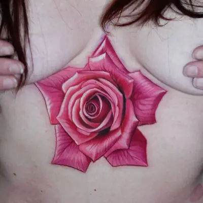 Realistic pink rose tattoo on chest area.