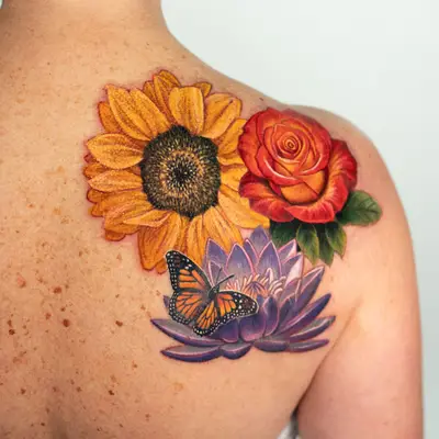 Colorful floral tattoo featuring a sunflower, rose, and butterfly on a person's back.