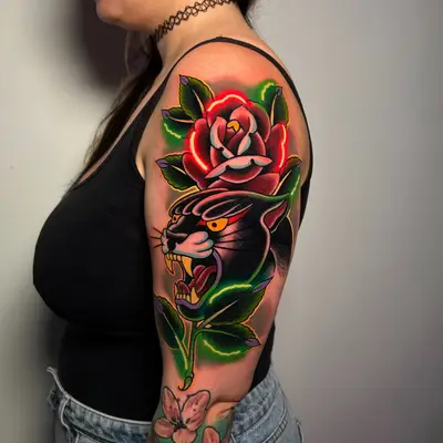 Colorful tattoo featuring a roaring panther and a rose on the upper arm.