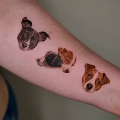Three small dog head tattoos on arm