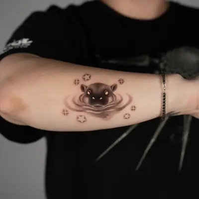 Black and grey tattoo of a stylized animal face with stars on arm.