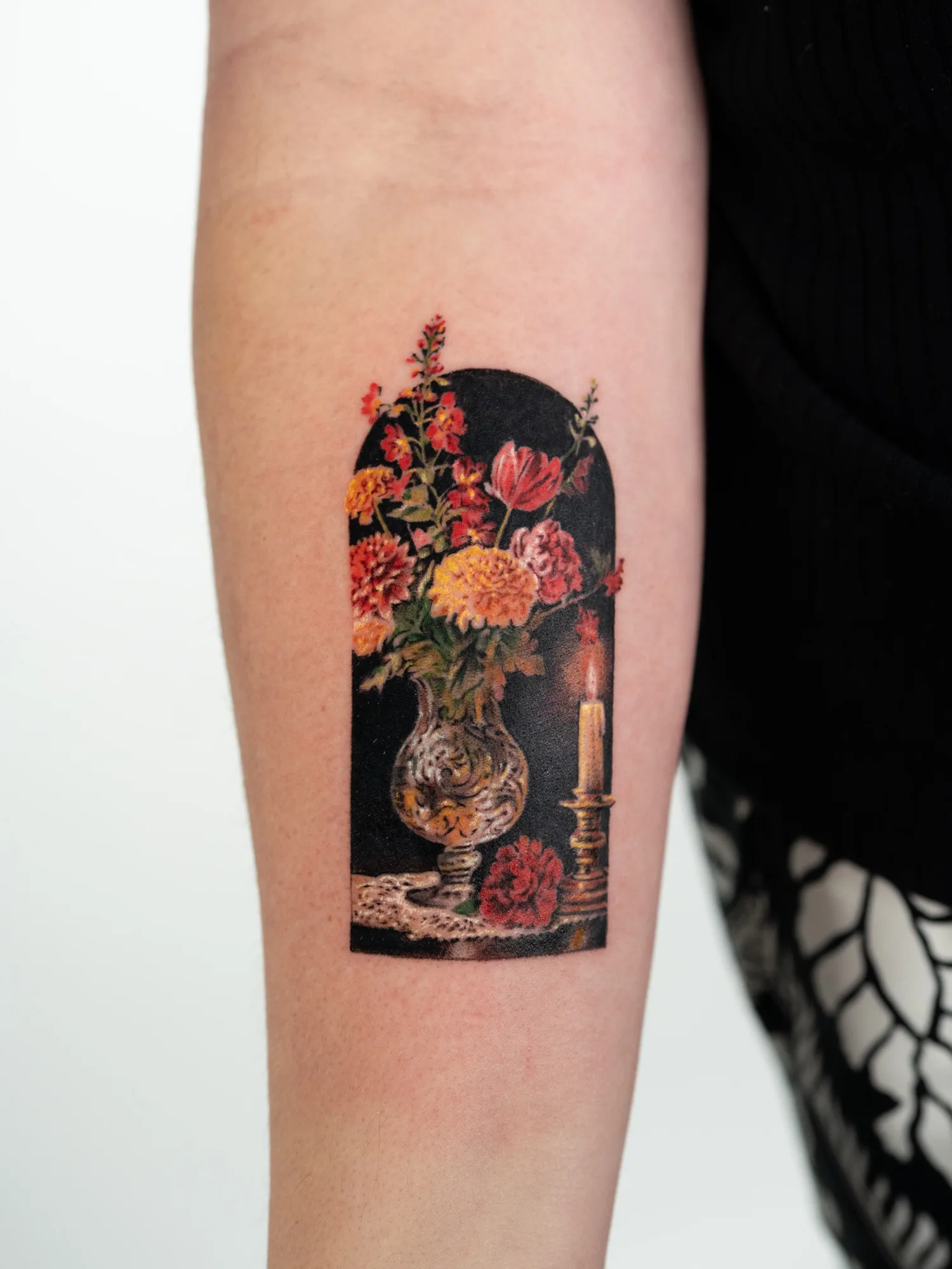 Still life tattoo of a flower vase and candle on forearm.