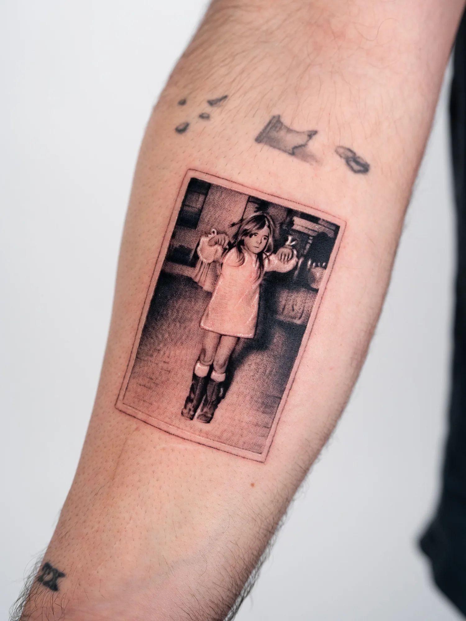 Arm tattoo depicting a young girl in a vintage style photo.