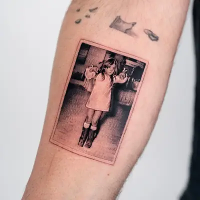 Arm tattoo depicting a young girl in a vintage style photo.