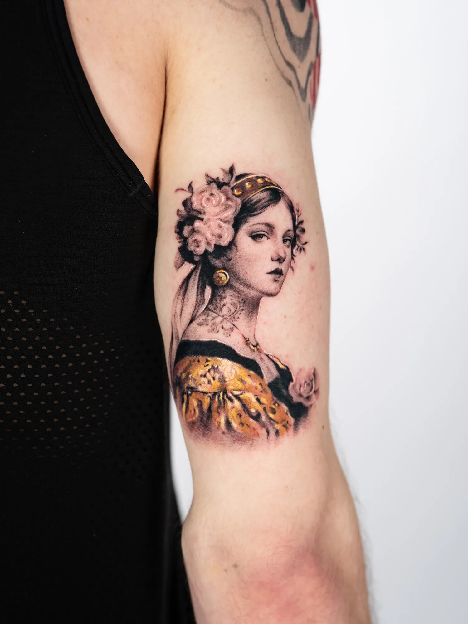 Tattoo of a woman with floral headpiece on upper arm.