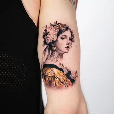 Tattoo of a woman with floral headpiece on upper arm.