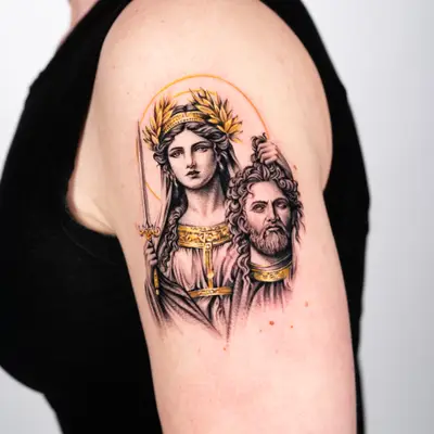 Tattoo of mythological figures on upper arm with laurel wreath and gold accents.