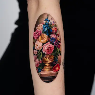 Realistic floral tattoo of a vase with flowers on a forearm.
