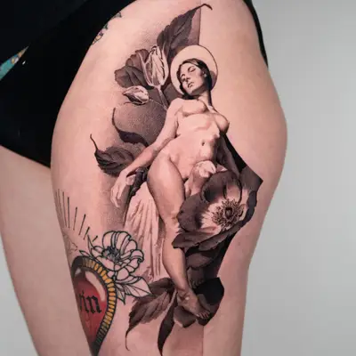 Tattoo of a nude figure with floral elements on a thigh.
