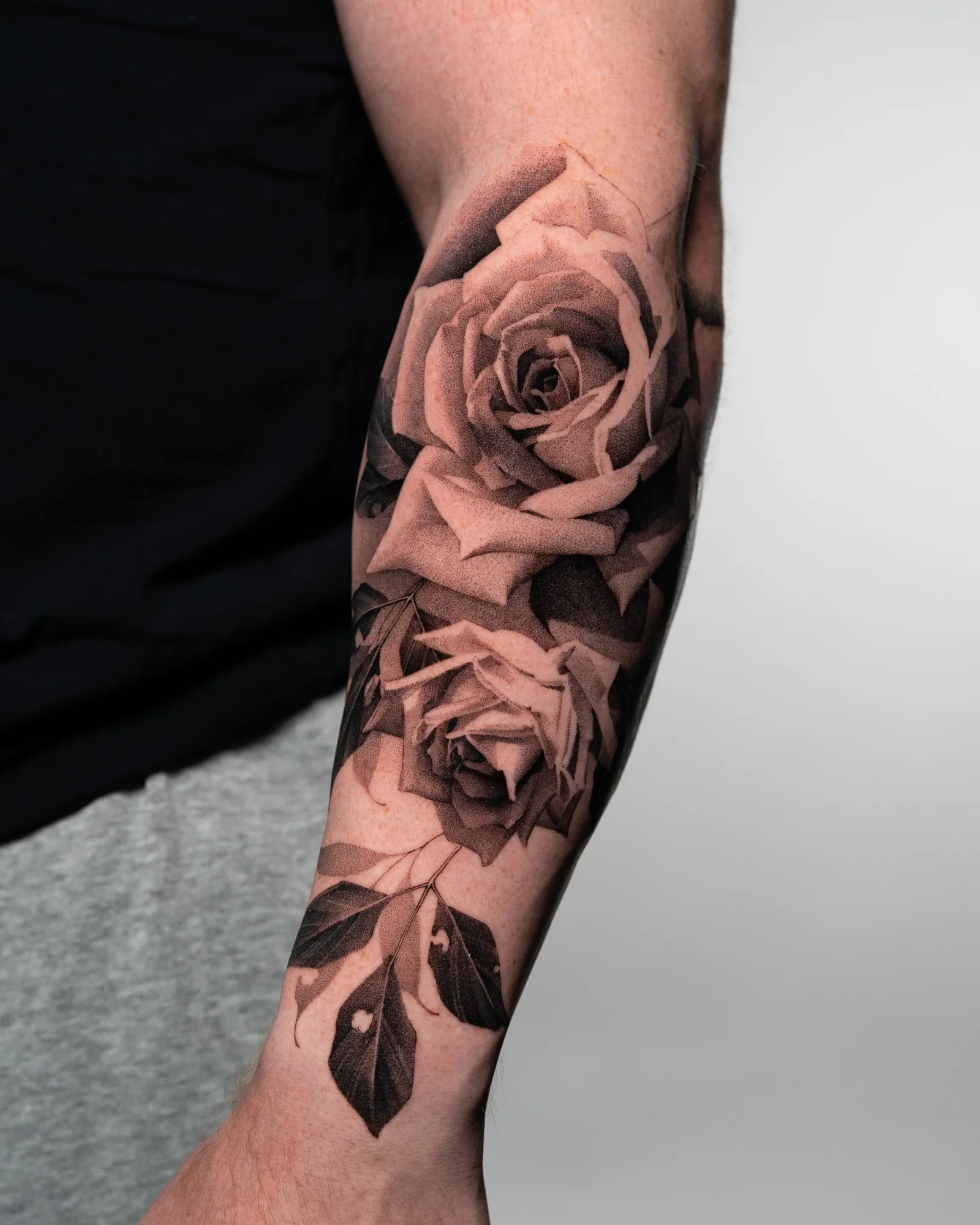 Black and grey rose tattoo on forearm.