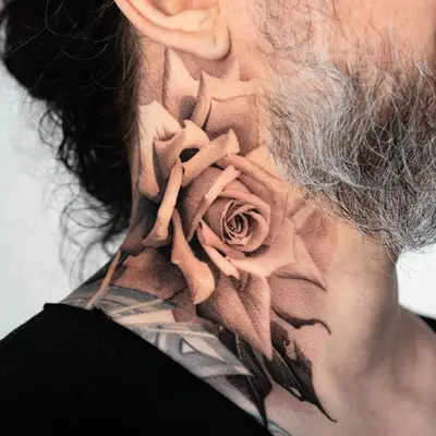 Black and grey rose tattoo on neck.
