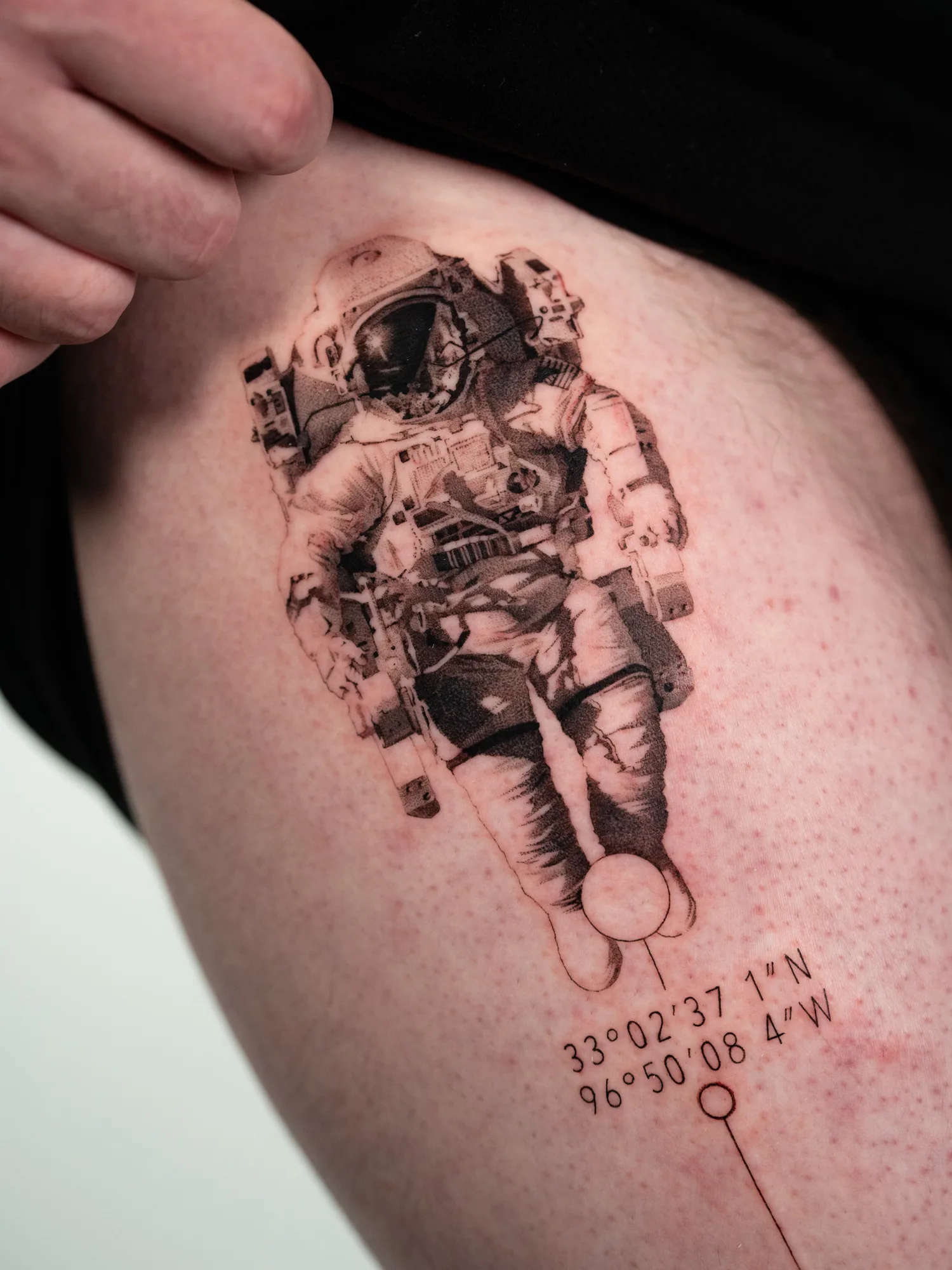 Tattoo of an astronaut with geographic coordinates.