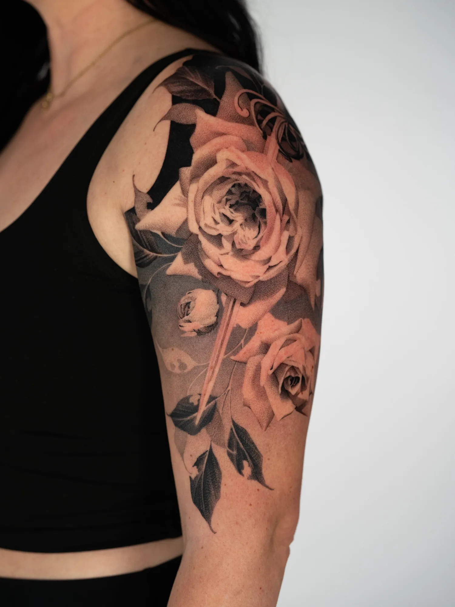 Black and grey floral tattoo on upper arm.