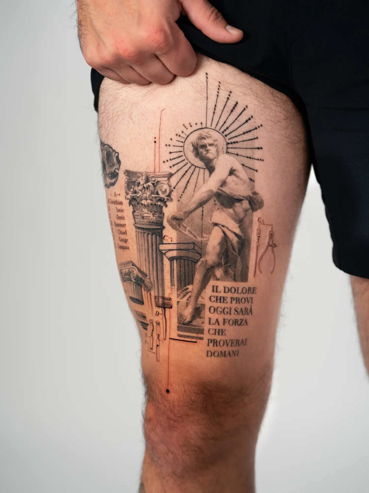 Thigh tattoo of a classical David statue with text and columns with a realism and fine line style.