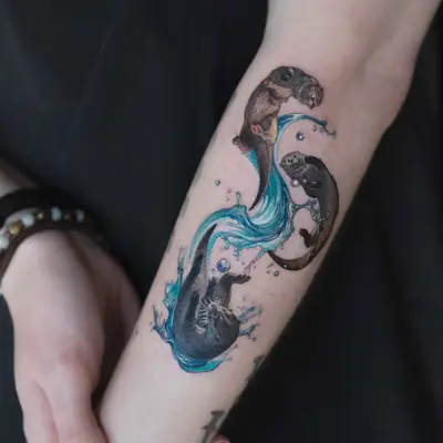 Tattoo of two otters and water on forearm