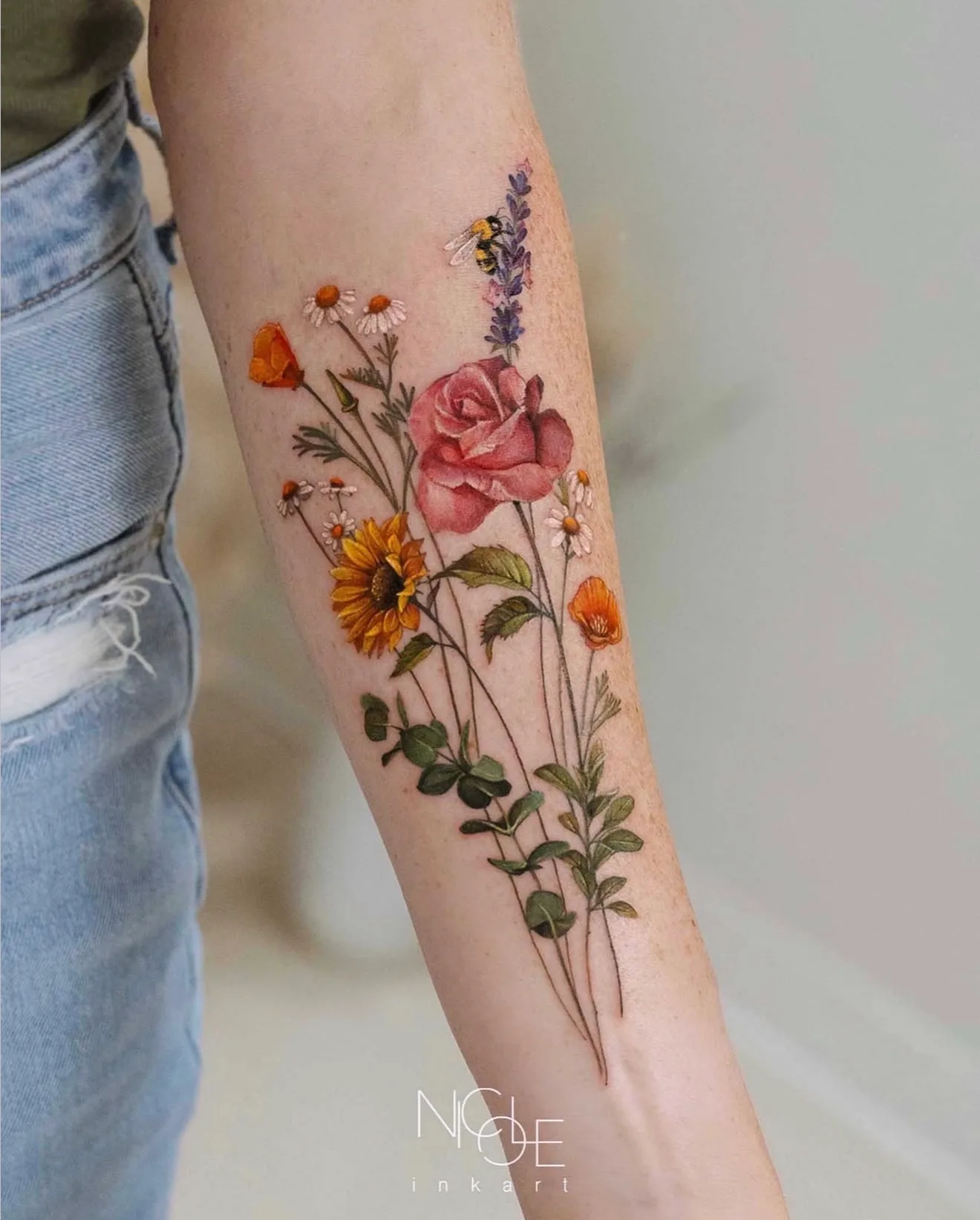Tattoo of colorful flowers and a bee on a forearm.