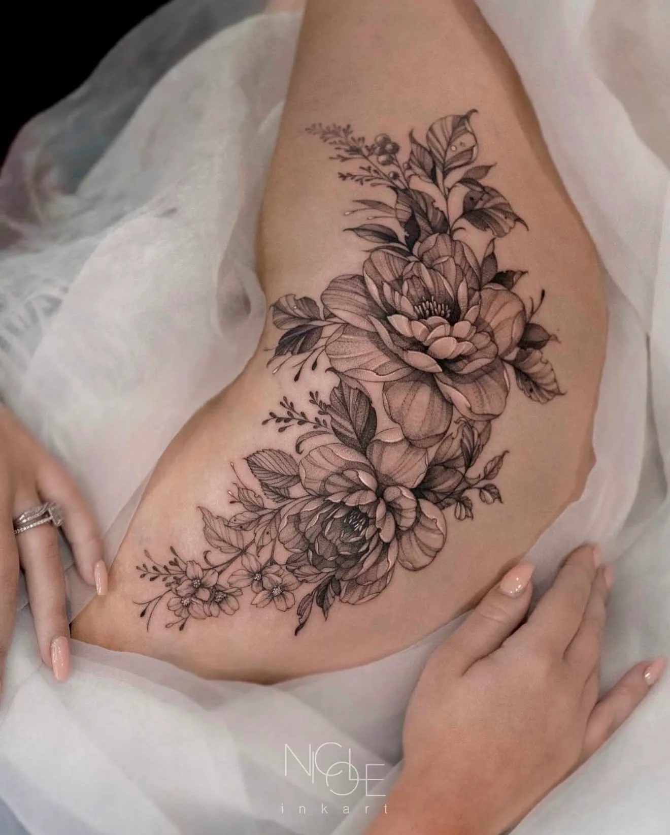 Black and grey floral tattoo on person's side.