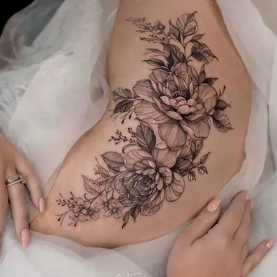 Black and grey floral tattoo on person's side.