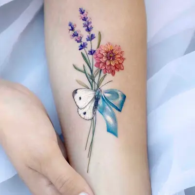 Colorful tattoo of lavender, a dahlia, and a butterfly with a blue ribbon.