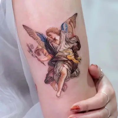 Tattoo of an angel with detailed wings holding flowers.