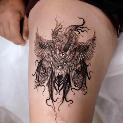 Complex tattoo with owl, eyes, and intricate designs on thigh.