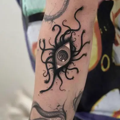 Tattoo of a central eye surrounded by abstract tentacles on arm