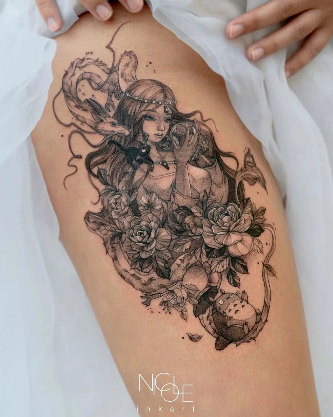 Intricate tattoo of a woman with a dragon and flowers on thigh.