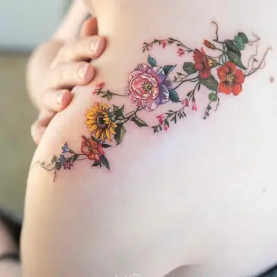 Colorful floral tattoo on upper arm with various flowers.