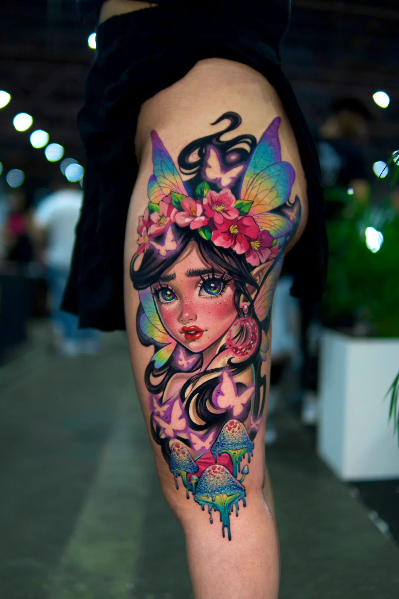 Colorful fairy tattoo with butterflies and mushrooms on the thigh.