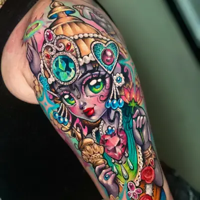 Color tattoo on the outer upper arm of a four-armed goddess in a doll-like style, wearing a jeweled gold crown and pearls and holding a pink lotus, a conch shell and a golden mace, with glitter gems and red roses.