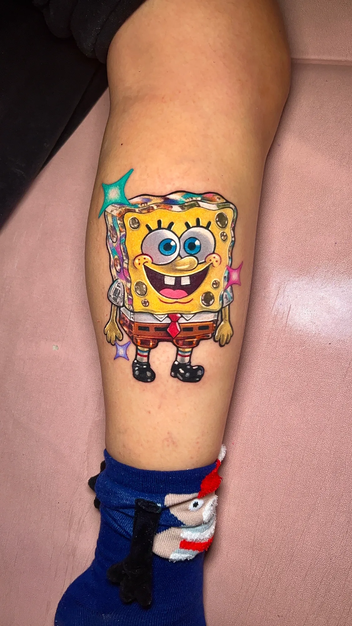 Colorful tattoo of a cartoon sponge character on a calf.
