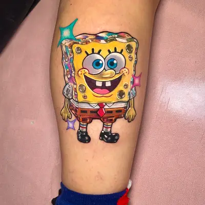 Colorful tattoo of a cartoon sponge character on a calf.
