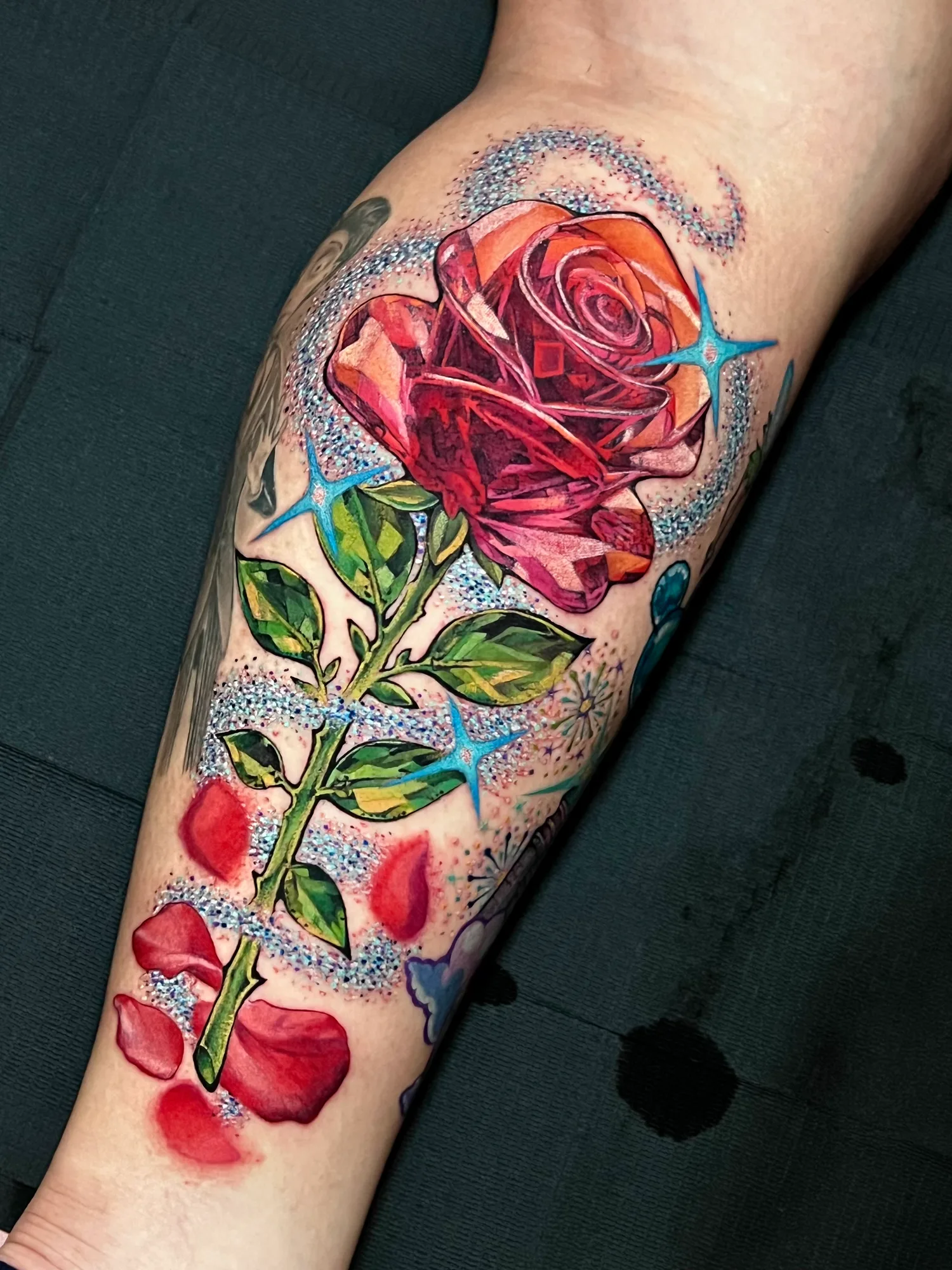 Bright colorful rose tattoo with abstract elements on calf.