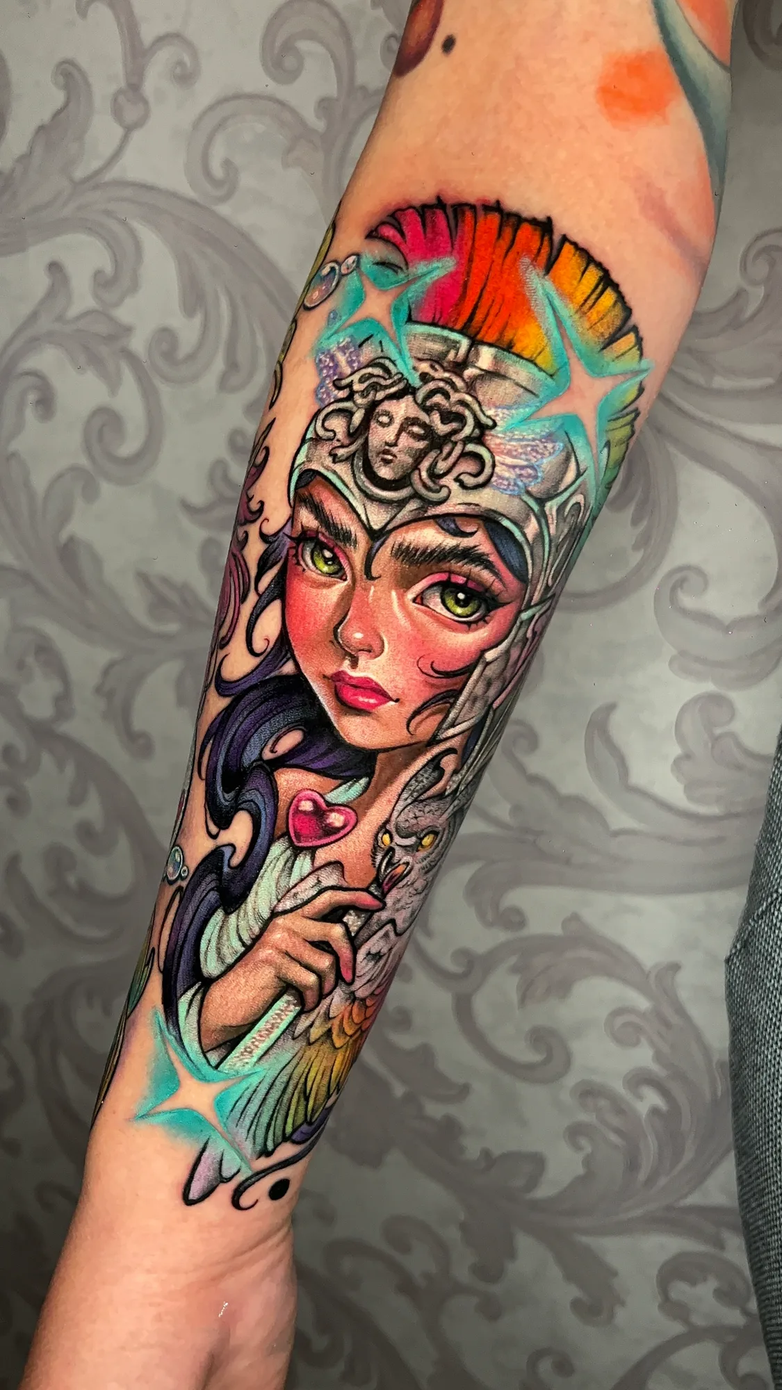 Colorful tattoo of a mythological female figure with an owl on her shoulder.