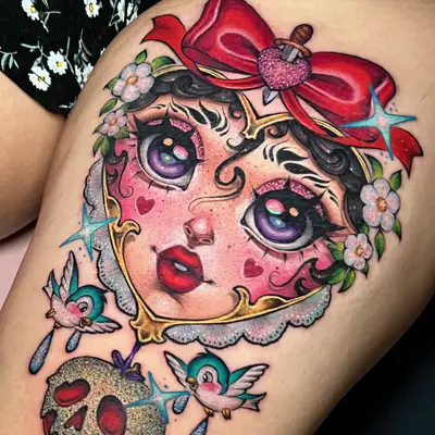 Colorful tattoo of a face with a bow, floral accents, birds, and a glittery skull.