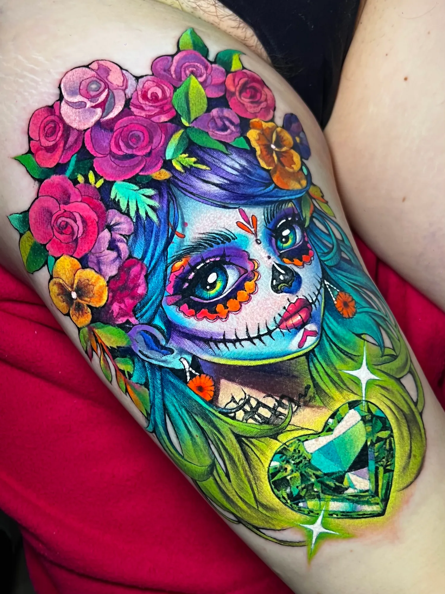 Colorful tattoo of a woman with a sugar skull face and floral headdress.