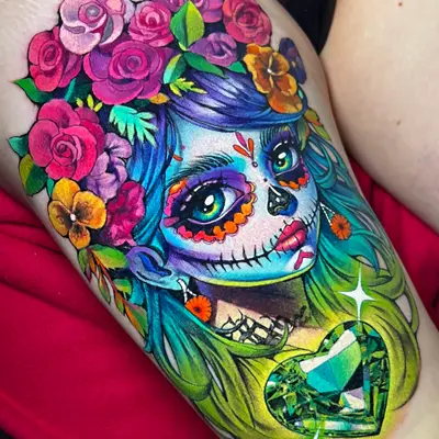 Colorful tattoo of a woman with a sugar skull face and floral headdress.