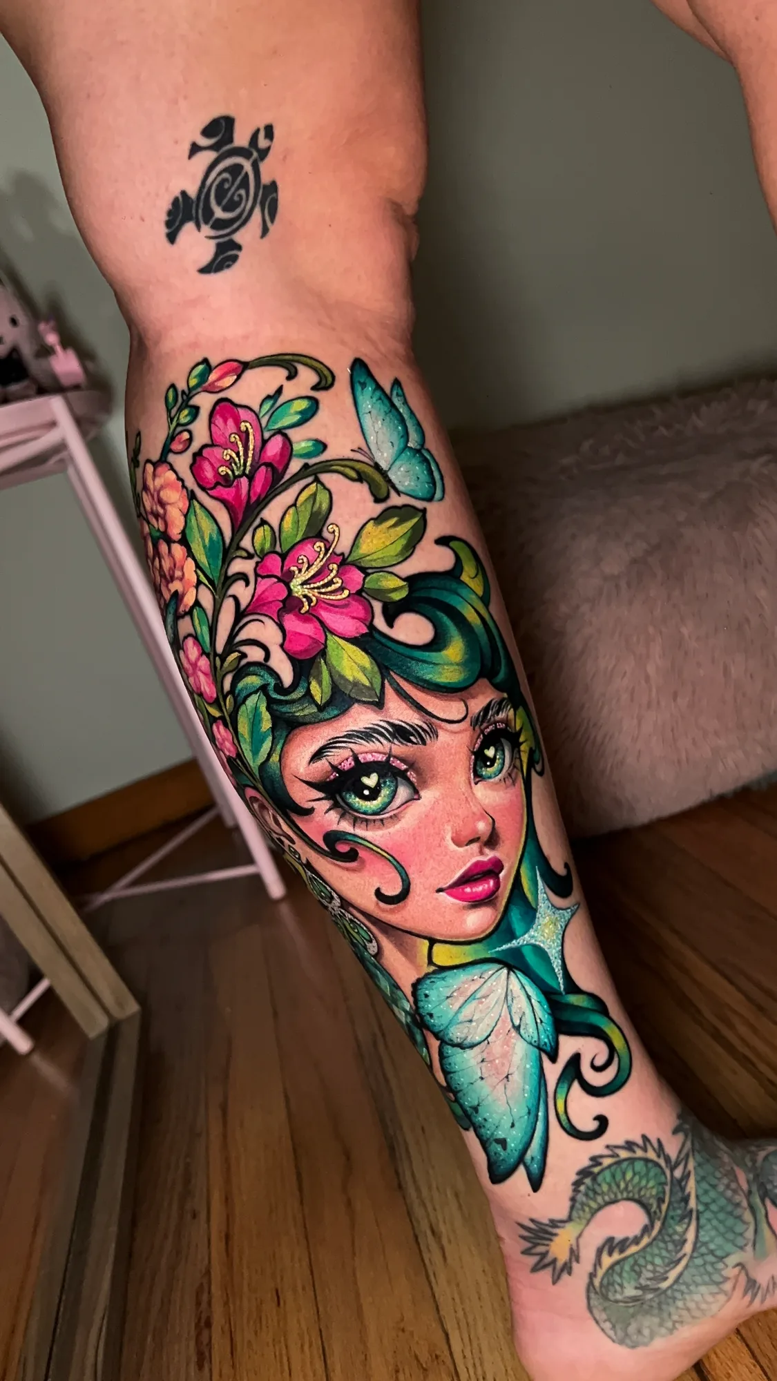 Colorful tattoo of a woman's face with floral and butterfly elements on leg